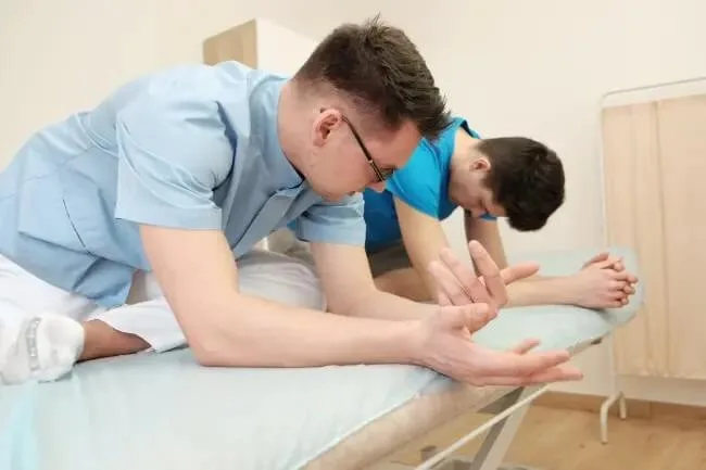 Fizjoterapeuta pokazuje pacjentowi ćwiczenie do samodzielnego wykonywania w domu